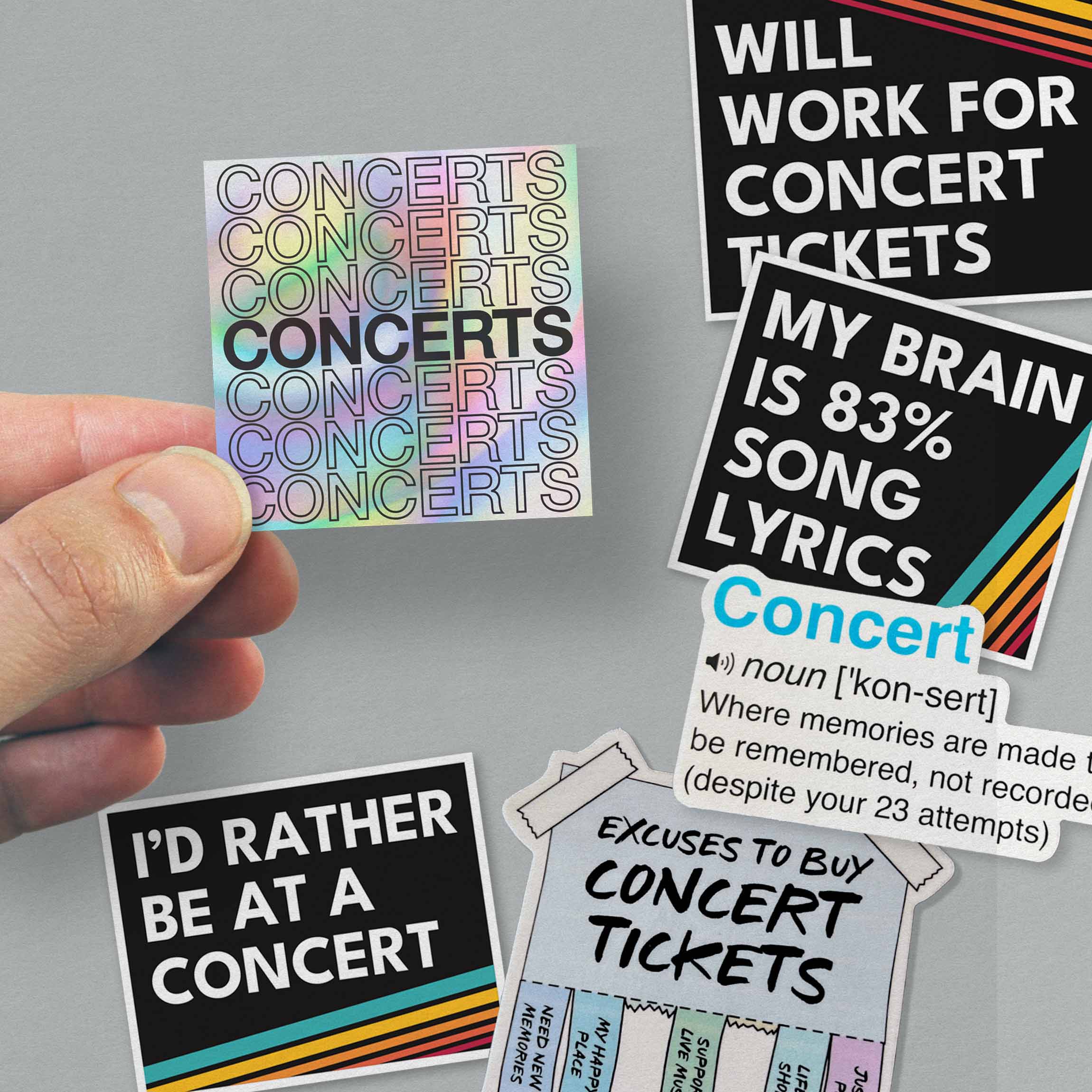 Hand holding three concert-themed vinyl stickers showcasing music quotes and designs.